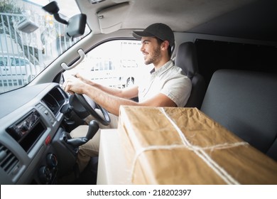 Delivery Driver Driving Van With Parcels On Seat Outside The Warehouse