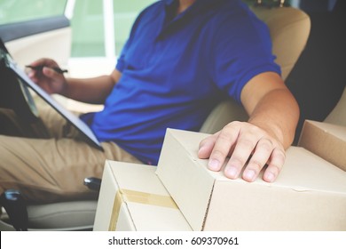 Delivery Driver Driving Van With Parcels On Seat Outside Warehouse