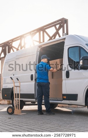 Delivery driver loading boxes into van for shipment. Delivery driver concept in a van. Man in blue uniform loading boxes into a delivery vehicle, representing logistics and shipping.