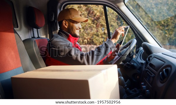 Delivery driver looking at\
tablet and then outside to confirm delivery address. High quality\
photo