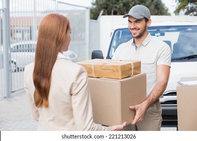 Delivery driver passing parcels to happy customer outside the warehouse