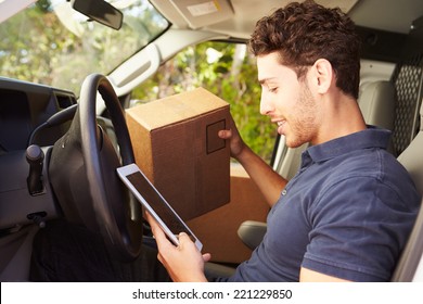 Delivery Driver Sitting In Van Using Digital Tablet