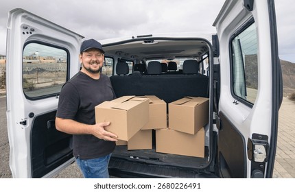 Delivery driver smiles while loading boxes outdoors. Copy space