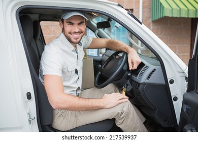 Delivery Driver Smiling At Camera In His Van Outside The Warehouse