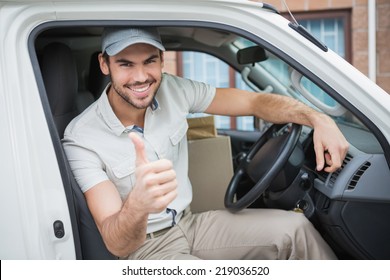 Delivery Driver Smiling At Camera In His Van Outside The Warehouse