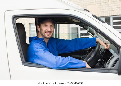 Delivery Driver Smiling At Camera In His Van Outside The Warehouse