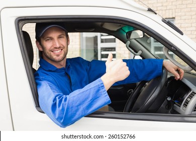 Delivery Driver Smiling At Camera In His Van Outside The Warehouse