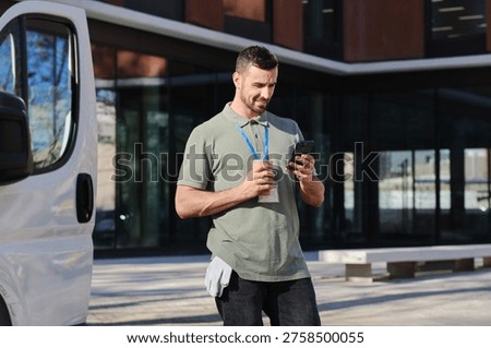 Delivery driver taking a break, drinking coffee and using smartphone next to delivery van