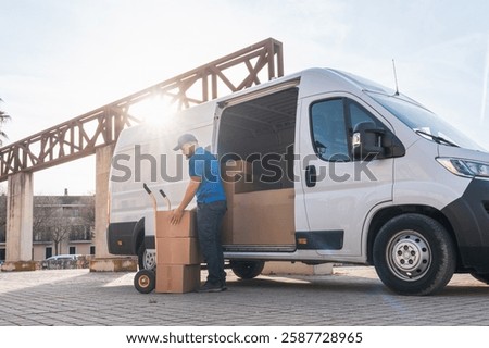 Delivery driver unloading packages from van with hand truck. Delivery driver concept in a van. Man in blue uniform using a hand truck to unload boxes from a delivery vehicle