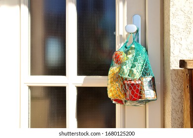 delivery during the quarantine. Shopping bag with Merchandise, goods and food is hanging at the front door, neighborhood Assistance concept at quarantine time because of coronavirus infection Covid-19 - Shutterstock ID 1680125200