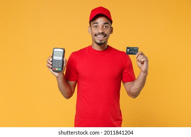 Delivery Employee African Man 20s In Red Cap T-shirt Uniform Work Courier Service Hold Wireless Bank Payment Terminal To Process And Acquire Credit Card Payments Isolated On Yellow Background Studio