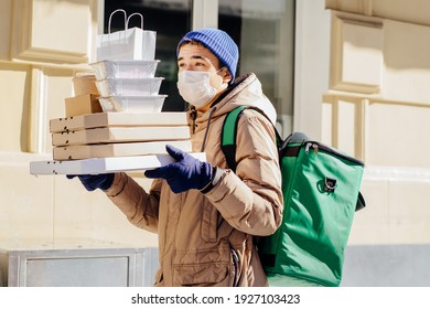 Delivery Employee Man In Facial Medical Maskat Thermal Takeaway Food Bag Backpack Pizza Boxes Work Courier Service Concept. Coronavirus Concept. Outdoor Winter Portrait.