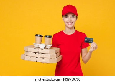 Delivery employee woman in red cap blank t-shirt uniform work courier service hold credit bank card give food order pizza in cardboard flatbox, paper cups of coffee tea isolated on yellow background