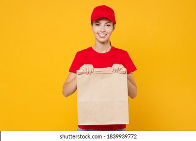 Delivery Employee Woman In Red Cap Blank T-shirt Uniform Work Courier Service From Shop Restaurant To Home Office Hold In Hand Brown Craft Paper Takeaway Food Bag Mockup Isolated On Yellow Background