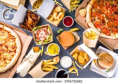 Delivery fastfood ordering food online concept. Large set of assorted take out foods pizza, french fries, fried chicken nuggets, burgers, salads, chicken wings, sides, black concrete background - Shutterstock ID 1996732682