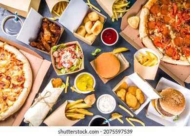 Delivery fastfood ordering food online concept. Large set of assorted take out foods pizza, french fries, fried chicken nuggets, burgers, salads, chicken wings, sides, black concrete background - Shutterstock ID 2075597539