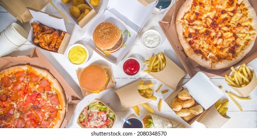 Delivery fastfood ordering food online concept. Large set of assorted take out foods pizza, french fries, fried chicken nuggets, burgers, salads, chicken wings, various sides, white table background  - Shutterstock ID 2080348570
