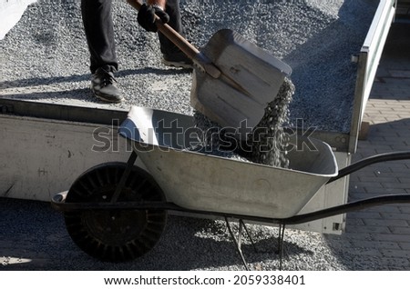 delivery of gray river pebbles, gravel as mulch for flower beds in the garden using a wheel from the body of a truck or trailer. shovel and raking. aluminum side truck