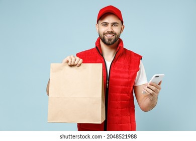 Delivery guy employee man in red cap white T-shirt vest uniform work as dealer courier service hold brown clear blank craft paper takeaway bag use cell phone isolated on pastel blue background studio - Powered by Shutterstock