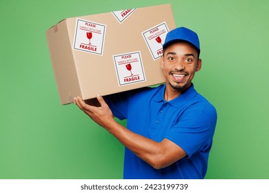 Delivery guy employee man wears blue cap t-shirt uniform workwear work as dealer courier hold blank cardboard box with fragile text sticker package isolated on plain green background. Service concept - Powered by Shutterstock