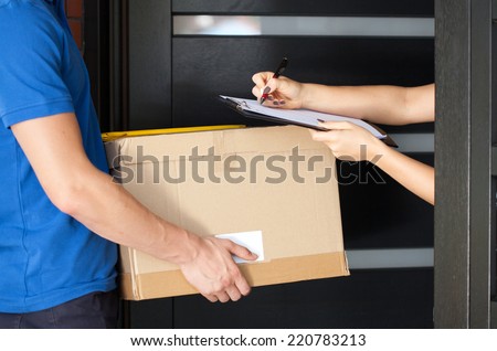 Delivery guy holding package while woman is signing documents