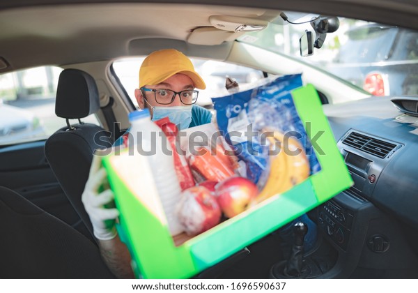 Delivery guy with protective mask\
and gloves delivering groceries during lockdown and\
pandemic.