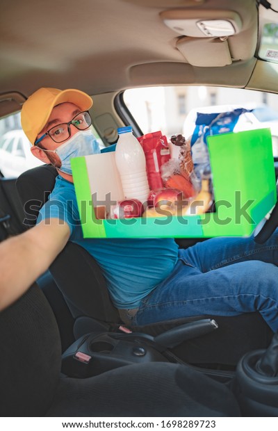 Delivery guy with protective mask\
and gloves delovering groceries during lockdown and\
pandemic.