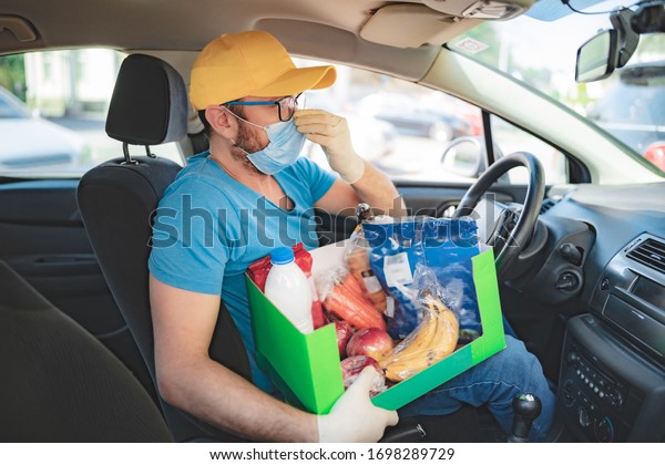 Delivery guy with protective mask\
and gloves delovering groceries during lockdown and\
pandemic.