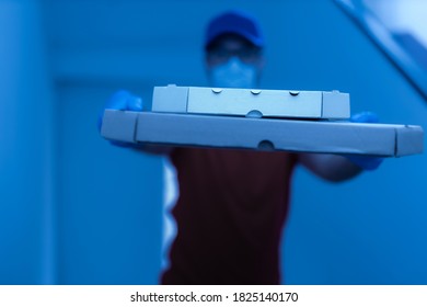 Delivery Guy With Protective Mask Holding Pizza Box At The Door.