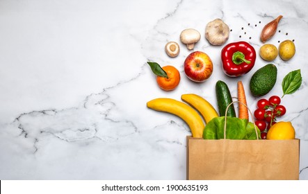 Lieferung von gesunden Lebensmitteln Hintergrund. Veganisches vegetarisches Essen in Papiersack Gemüse und Früchte auf weißem Marmor Hintergrund, Banner. Lebensmittelgeschäft Supermarkt und reines veganisches Esskonzept.