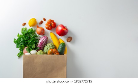 Delivery healthy food background. Healthy vegan vegetarian food in paper bag vegetables and fruits on white, copy space, banner. Shopping food supermarket and clean vegan eating concept - Shutterstock ID 1932772715