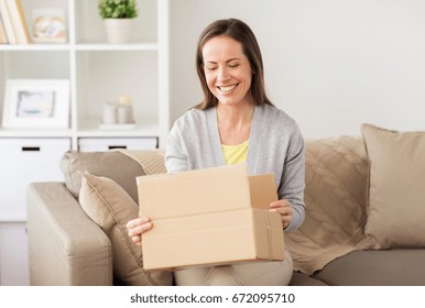 delivery, mail and people concept - smiling woman opening cardboard box at home