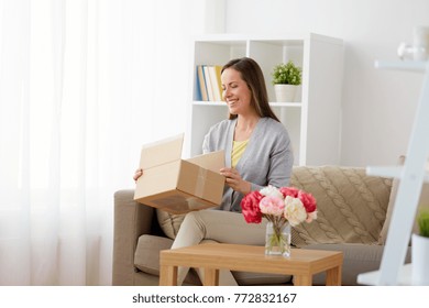 delivery, mail and people concept - smiling middle-aged woman opening parcel box at home