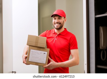 Delivery, Mail, People And Shipment Concept - Happy Man In Red Uniform With Parcel Boxes In Corridor At Open Customer Door