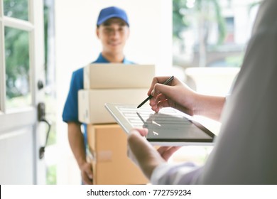 delivery, mail, people and shipping concept.Young woman sign in digital mobile phone after receiving parcel from courier at home. - Shutterstock ID 772759234