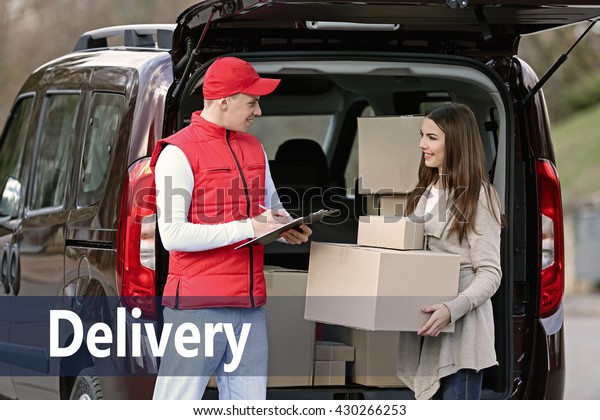 Delivery man and attractive young woman\
receiving a package, near the car\
outdoors