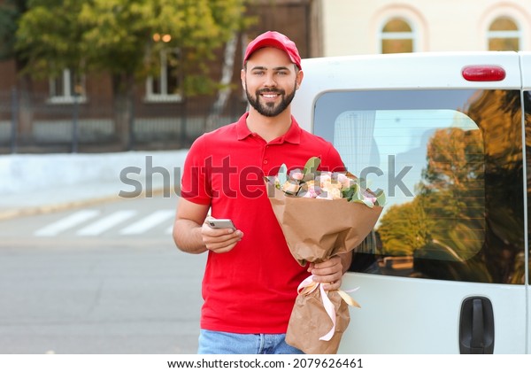 Delivery man with bouquet of beautiful flowers\
and mobile phone near car\
outdoors
