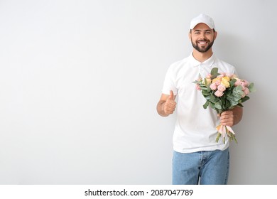 Delivery Man With Bouquet Of Flowers Showing Thumb-up On Light Background