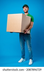 Delivery Man With Box In Studio Against Blue Background