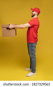 Delivery man with box in studio isolated on yellow background.