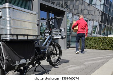 Delivery Man With Cargo Ebike And Box In Front Of An Office Building Entrance.