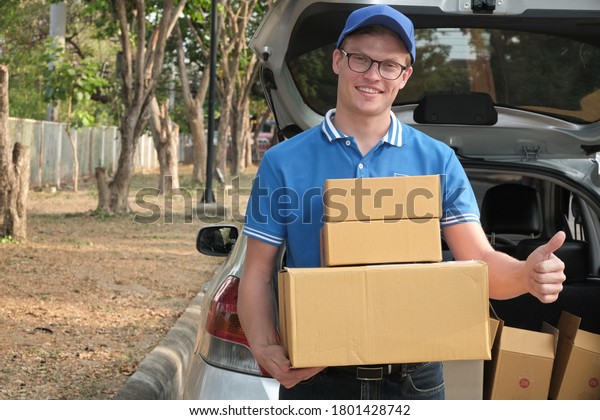 delivery man carrying\
packgage at back of car. male postal courier person deliver\
cardboard parcel box