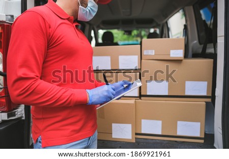 Delivery man checking with digital tablet the package while wearing surgical face mask for coronavirus - Work with new safety mesaures