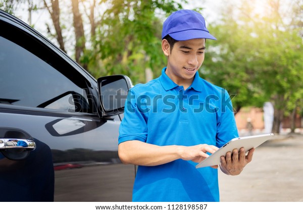 Delivery man checking
document list on clipboard outdoor and Cardboard Boxes, Package
delivery concept