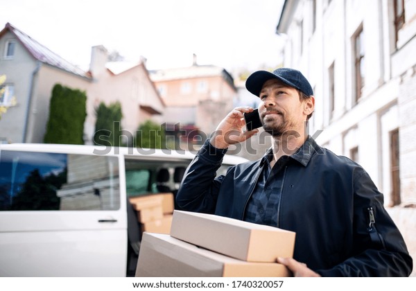 Delivery man courier delivering parcel box in
town using smartphone.