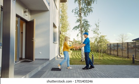 Delivery Man Delivers Cardboard Box Package to a Beautiful Young Woman, Who will Sign Electronic Signature POD Device. In the Background Cute Suburban Neighbourhood. Side View Shot