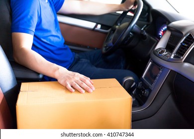 Delivery man driving a truck with cardboard package on the front seat