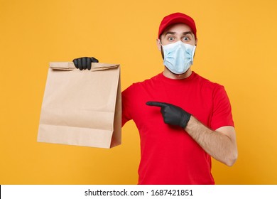 Delivery Man Employee In Red Cap T-shirt Uniform Mask Glove Hold Craft Paper Packet With Food Isolated On Yellow Background Studio Service Quarantine Pandemic Coronavirus Virus 2019-ncov Concept