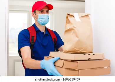 Delivery man employee in red cap t-shirt uniform mask gloves give food order pizza boxes isolated on yellow background studio. Service quarantine pandemic coronavirus virus flu 2019-ncov concept