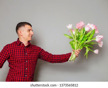 A Delivery Man Holding A Beautiful Bouquet Isolated On Grey Background. Romantic Gift. How To Be Gentleman. Womens Day. Flower For March 8. Surprise Concept. Cute Funny Emotional Man